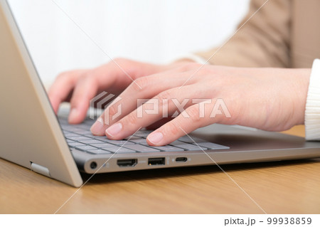 ノートパソコンのキーボードをタイピングする女性の手元 99938859
