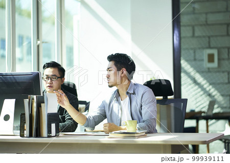 two young asian business people working together in office discussing business 99939111