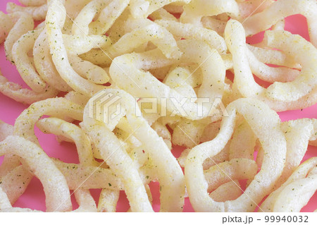 A bunch of crunchy onion rings close up on a pink background. Snack onion rings. A bunch of crunchy onion rings close up on a pink background. Snack onion rings. 99940032