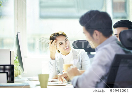 three young asian entrepreneurs sitting at desk discussing business three young asian entrepreneurs sitting at desk discussing business 99941002