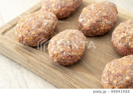 raw homemade meatballs on a massive board made of natural wood raw homemade meatballs on a massive board made of natural wood 99941488