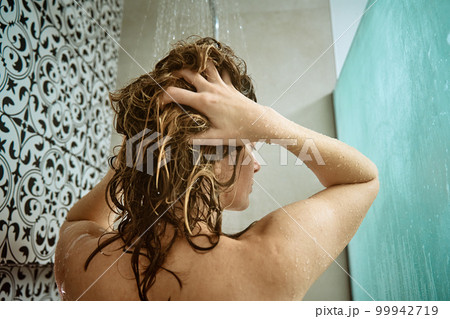 Back view of naked woman taking shower in shower stall. Woman washing her hairs in bathroom. Morning hygiene Back view of naked woman taking shower in shower stall. Woman washing her hairs in bathroom. Morning hygiene 99942719