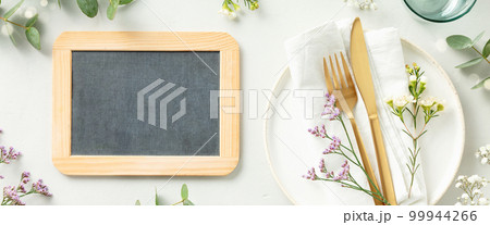 Gold Cutlery with chalk board, eucalyptus branches on white plate with napkin over light grey Background. Minimalistic design. Copy Space banner 99944266