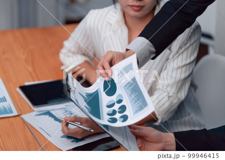 Focus closeup report papers on harmony workplace with blur businesspeople. Focus closeup report papers on harmony workplace with blur businesspeople. 99946415