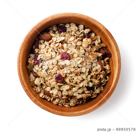 Granola with nuts and raisins in a wooden plate on a white background. Top view 99950579