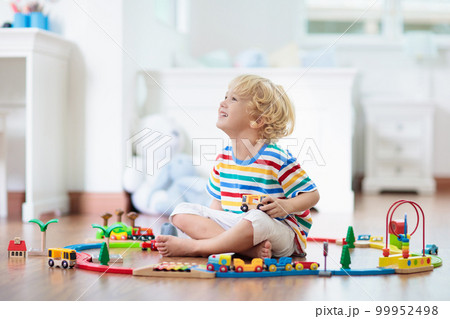 Kids play wooden railway. Child with toy train. Kids play wooden railway. Child with toy train. 99952498