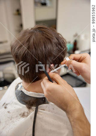 young caucasian man getting haircut by professional male hairstylist 99955962
