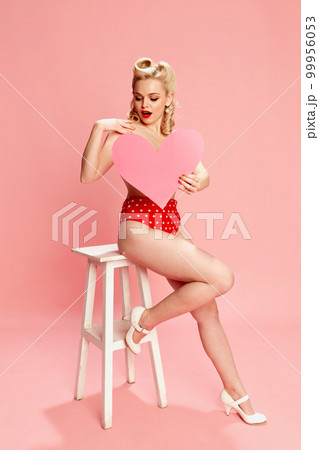 Summer vacation. Portrait of beautiful young girl in swimming suit posing against pink studio background. Concept of beauty and pin-up style Summer vacation. Portrait of beautiful young girl in swimming suit posing against pink studio background. Concept of beauty and pin-up style 99956053