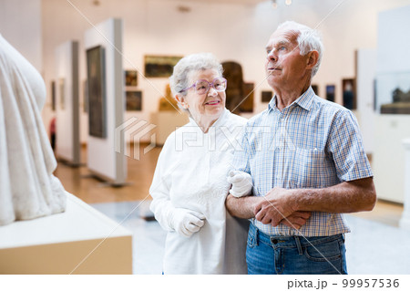 mature European couple examines paintings in an exhibition in hall of art museum 99957536