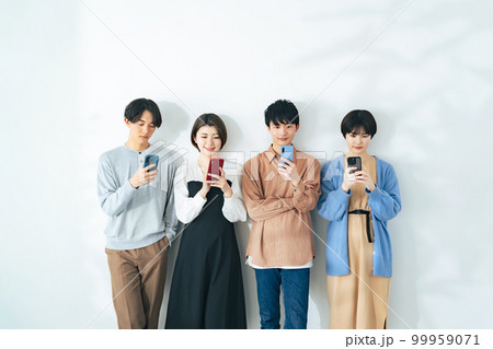 並んでスマホを見る若い4人グループ 並んでスマホを見る若い4人グループ 99959071