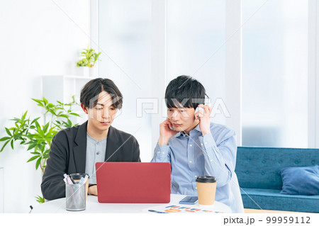 ノートパソコンを見る二人の若い男性 99959112