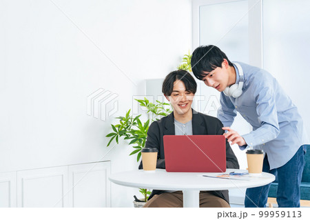 ノートパソコンを見る二人の若い男性 99959113