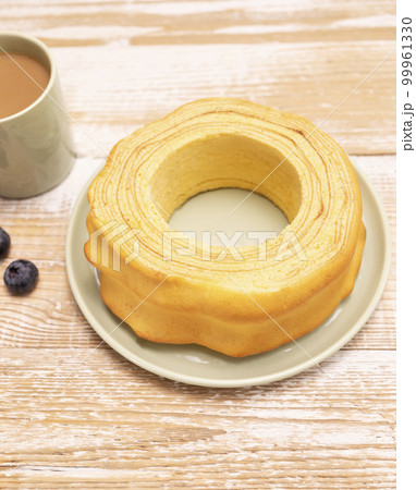 Baumkuchen, sakotis ,sekacz on wooden rustic table with cup of coffee, blueberries, traditional spit cake of lithuanian, polish, german, belarusian cuisine made of butter,eggs,flour,sugar. Vertical Baumkuchen, sakotis ,sekacz on wooden rustic table with cup of coffee, blueberries, traditional spit cake of lithuanian, polish, german, belarusian cuisine made of butter,eggs,flour,sugar. Vertical 99961330