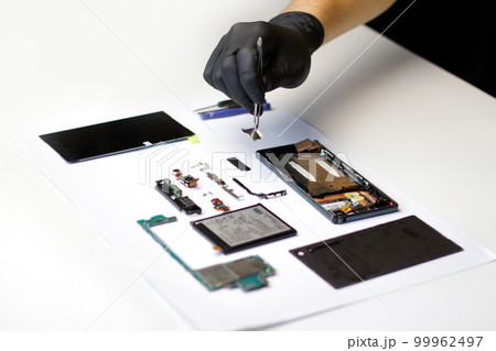 Repairman. Defocus technician repairing the smartphone's motherboard in the lab. Mobile phone, electronic, repairing, upgrade and technology. Disassembling components broken smartphone 99962497
