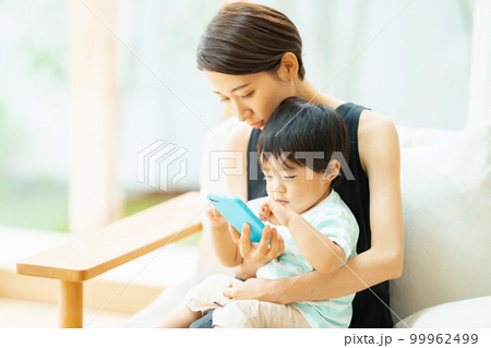 2歳の男の子とスマホで動画を見る母親 99962499