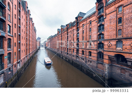 Touristic cruise boat on a channel with bridges in the warehouse district Speicherstadt in Hamburg, Germany 99963331