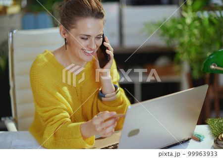 smiling business owner woman in green office talking on phone 99963933