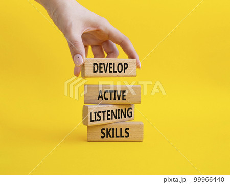 Listening skills symbol. Concept word Develop active listening skills on wooden blocks. Beautiful yellow background. Businessman hand. Business and Develop active listening skills concept. Copy space 99966440