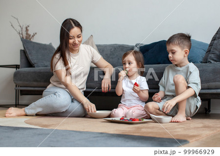 Mother and children have breakfast on the floor. Mother and children have breakfast on the floor. 99966929