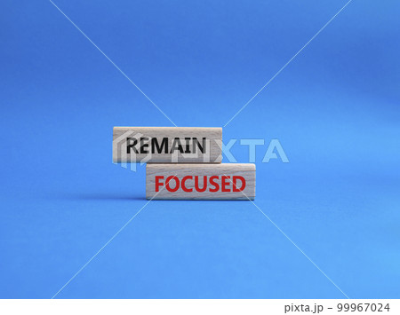 Remain focused symbol. Concept words Remain focused on wooden blocks. Beautiful blue background. Business and Remain focused concept. Copy space. 99967024