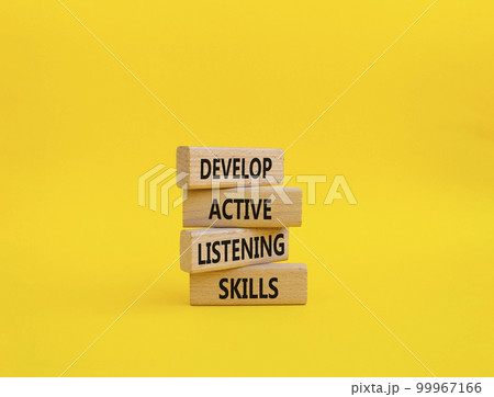 Listening skills symbol. Concept word Develop active listening skills on wooden blocks. Beautiful yellow background. Business and Develop active listening skills concept. Copy space 99967166