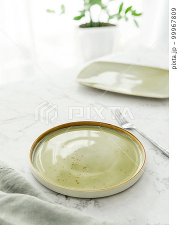 Empty green plate with tablecloth and fork on white marble table Empty green plate with tablecloth and fork on white marble table 99967809