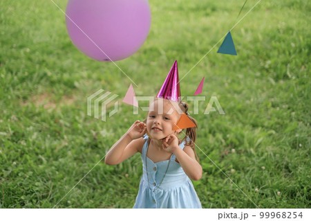 Funny humorous girl playing with a festive garland of colorful flags and balloons Funny humorous girl playing with a festive garland of colorful flags and balloons 99968254