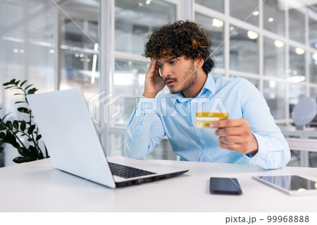 Upset and deceived businessman inside office trying to transfer money online, nervous man holding bank credit card, got rejected and error of funds on account negative balance. Upset and deceived businessman inside office trying to transfer money online, nervous man holding bank credit card, got rejected and error of funds on account negative balance. 99968888