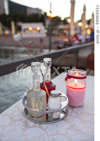 The terrace of the restaurant by the sea, there is a candle on the table. Against the backdrop of a beautiful resort town. Romantic dinner by the sea. 99969431
