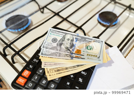 Banknotes lie next to a burning gas burner along with a calculator. The concept is to increase the cost of supply and payment for natural gas. 99969471