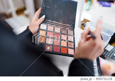 Woman with a make-up palette with different mascara shades 99970128
