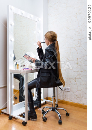 Rear view of a woman making up on a backstage 99970129