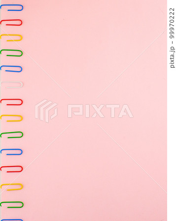 Pink paper sheet fixed with multi-colored paper clips close, for background, vertical 99970222