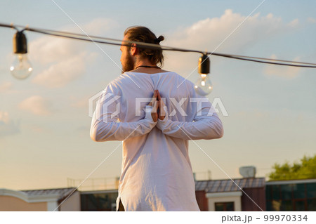 man on the roof doing yoga on the background of the setting sun man on the roof doing yoga on the background of the setting sun 99970334
