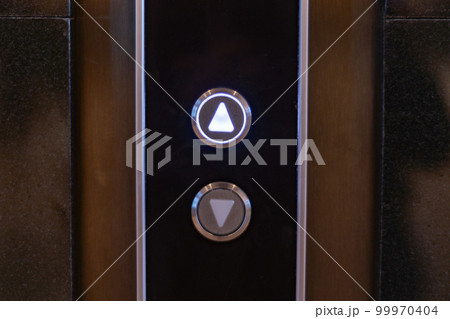 elevator call buttons on a brown wooden panel elevator call buttons on a brown wooden panel 99970404