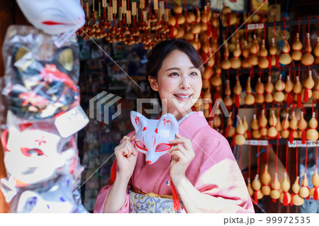 京都の土産物店で狐のお面を持つ着物姿の女性 99972535