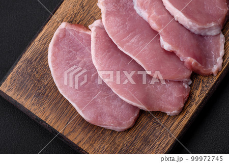 Fresh juicy pork on a wooden cutting board with spices and salt Fresh juicy pork on a wooden cutting board with spices and salt 99972745