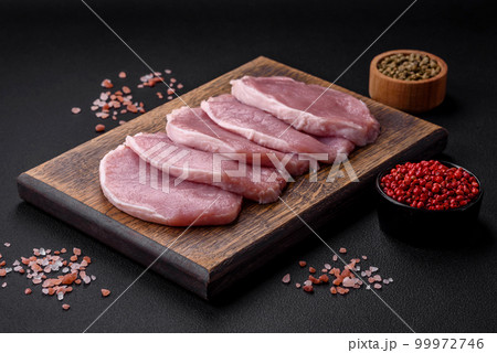 Fresh juicy pork on a wooden cutting board with spices and salt Fresh juicy pork on a wooden cutting board with spices and salt 99972746