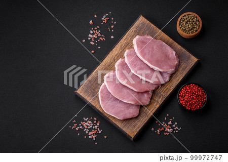 Fresh juicy pork on a wooden cutting board with spices and salt 99972747