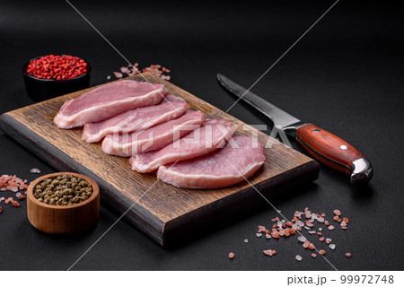 Fresh juicy pork on a wooden cutting board with spices and salt Fresh juicy pork on a wooden cutting board with spices and salt 99972748