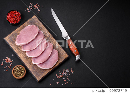 Fresh juicy pork on a wooden cutting board with spices and salt Fresh juicy pork on a wooden cutting board with spices and salt 99972749