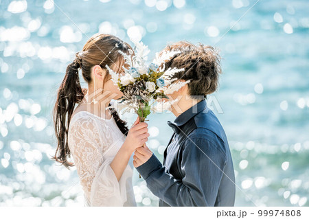 ブーケを持ち顔を見合わせる新郎新婦 99974808