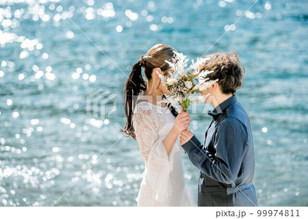 ブーケを持ち顔を見合わせる新郎新婦 ブーケを持ち顔を見合わせる新郎新婦 99974811