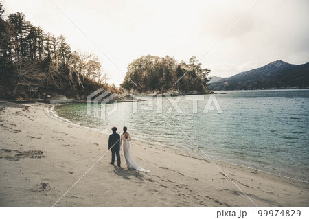 海辺を楽しそうに歩く新郎新婦 99974829