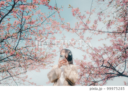 桜バックに音楽を聴く女性の写真 桜バックに音楽を聴く女性の写真 99975285