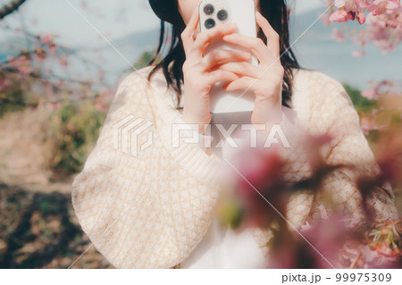 桜バックに音楽を聴く女性の写真 桜バックに音楽を聴く女性の写真 99975309