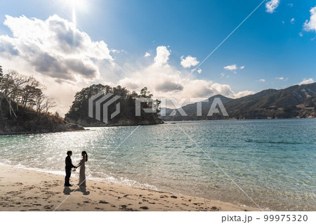 海辺で顔を見合わせる新郎新婦 海辺で顔を見合わせる新郎新婦 99975320