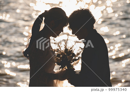 海辺で顔を見合わせる新郎新婦 海辺で顔を見合わせる新郎新婦 99975340