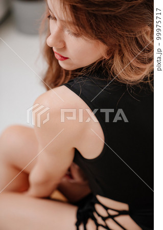 a long-haired woman in a black sexy tight dress with a lace on her thigh 99975717