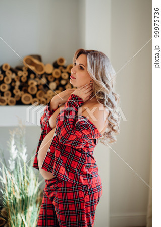 A Pregnant Woman Topless In Pajama Pants In Profile In A Home